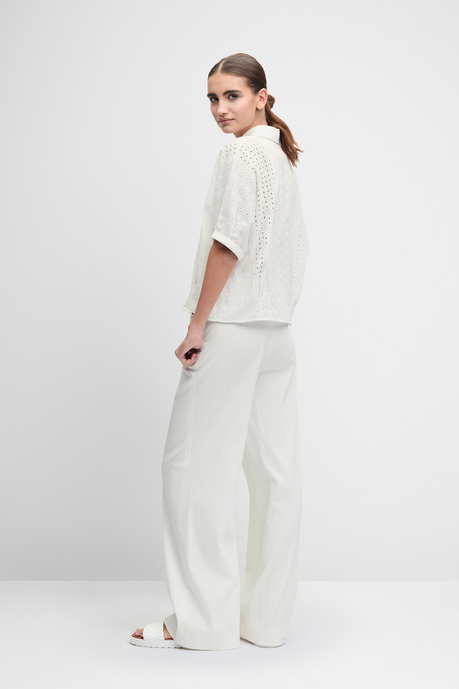 Weißes Oberteil, Weites Beinkleid, Perforiertes Muster, Lederjacke (braune), gehalten, Weiße Hose