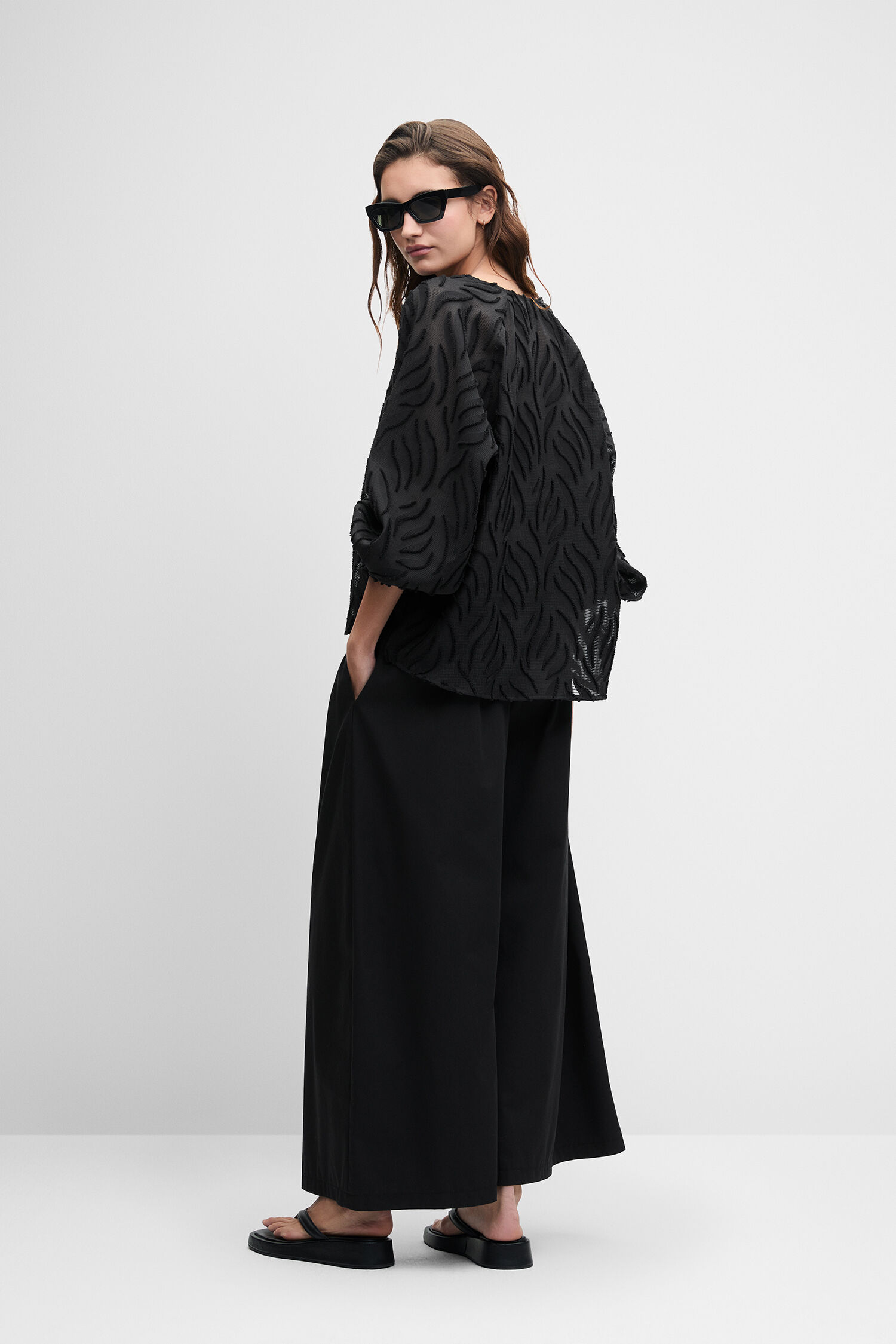 schwarzes Top, gemustertes Blouson, weiterweite Hose, Sonnenbrille, Slipper-Sandalen